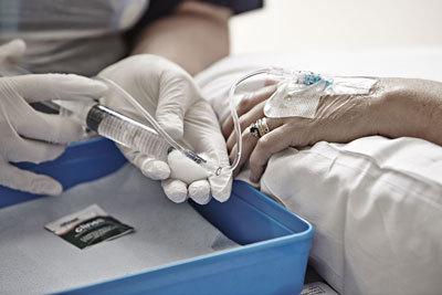 Photograph of someone having chemotherapy into a vein in their hand through a cannula.